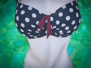 Summer background. Large polka dot bikini on a mannequin on a turquoise background, retro style