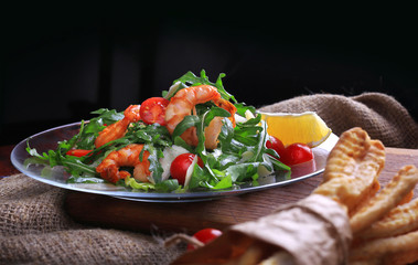 Salad with arugula and cherry tomatoes with shrimp, slices of lomon and parmesan.