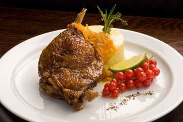 Grilled turkey leg with mashed potatoes decorated with red currants.