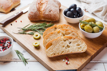 Italian ciabatta bread with olives and rosemary on a wooden Board.