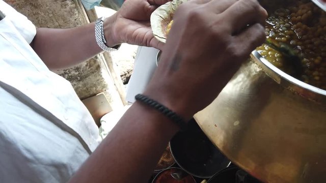 Street food- Chole Kulche- popular fast meal with dry chickpeas spicy masala mixture with maida based bread Kulcha in India, Pakistan and Bangladesh.  4k slow-motion close-up stabilized handheld 