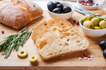 Italian ciabatta bread with olives and rosemary on a wooden Board.