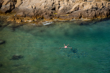 Aerial view of a person swimming in torquoise ocean