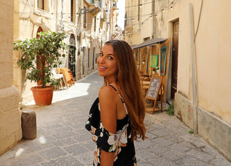 Happy smiling beautiful woman in flowered summer dress walking joyful and cheerful in Syracuse,...