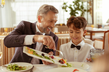 Aged groom giving some salad for his grandson