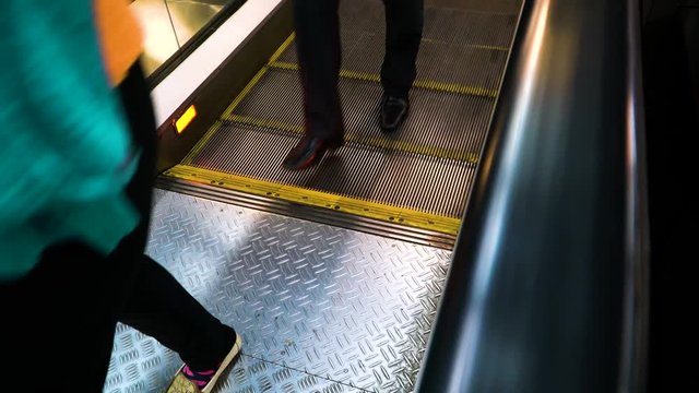 People descend from a moving escalator on the rise.