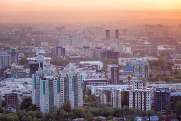 Beautiful top view of the big industrial city of Almaty in the pink light of sunset.