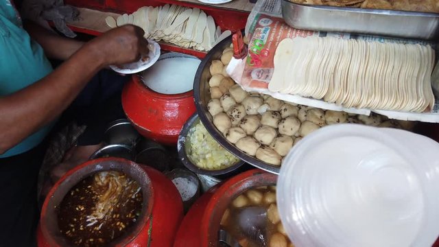 Street food- Dahi bhalla and Papri chaat, soaking vadas in thick curd, popular traditional fast food using crisp fried dough wafers in India and Pakistan. 4k 60fps close-up stabilized handheld 