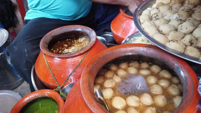 Street food- Dahi bhalla and Papri chaat, soaking vadas in thick curd, popular traditional fast food using crisp fried dough wafers in India and Pakistan. 4k 60fps close-up stabilized handheld 