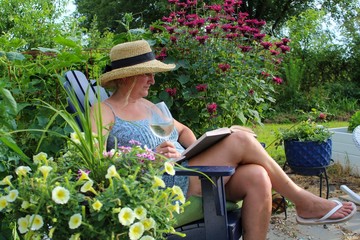 Relaxed and Happy Mature Adult Woman 50-59 enjoying a glass of wine in her garden glass