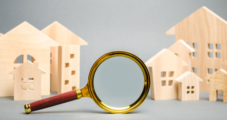 Magnifying glass and wooden houses. House searching concept. Home appraisal. Property valuation....