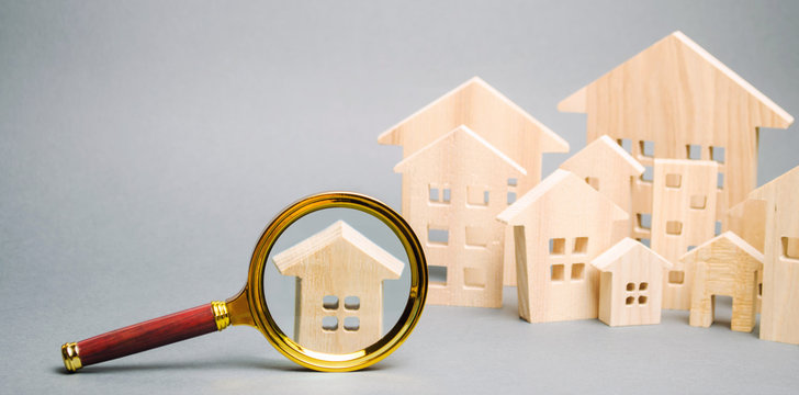 Magnifying Glass And Wooden Houses. House Searching Concept. Home Appraisal. Property Valuation. Choice Of Location For The Construction. Search For Housing, Apartments. Real Estate Appraiser Services