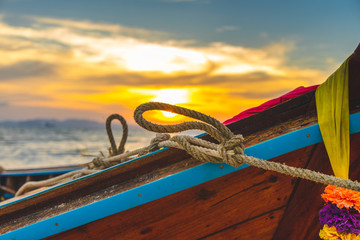 Traditional Long tail Thai Boat resting on the beach as the sun sets on a beautiful Krabi beach, perfect sunset at a dream destination, holiday, vacation.