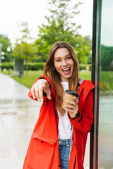 Fototapeta premium Cheerful attractive young girl wearing raincoat