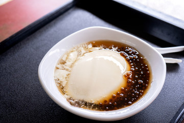 Popular Taiwan gourmet - Dessert of tapioca pearl ball (bubble) mixed bean curd tofu pudding (douhua, dou hua) in white bowl, close up, lifestyle