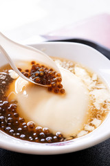 Popular Taiwan gourmet - Dessert of tapioca pearl ball (bubble) mixed bean curd tofu pudding (douhua, dou hua) in white bowl, close up, lifestyle