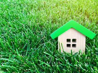 Miniature wooden house on green grass. Real estate concept. Eco-friendly and energy efficient...