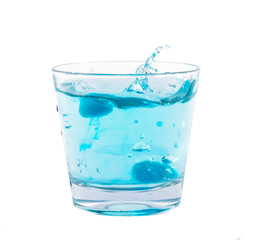 Blue ice cubes splashing into glass of water.