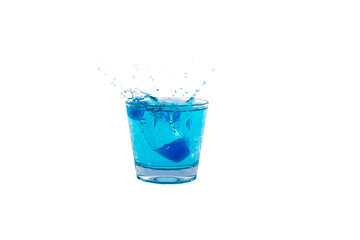 Blue ice cubes splashing into glass of water