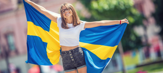 Happy girl tourist walking in the street with sweden flag
