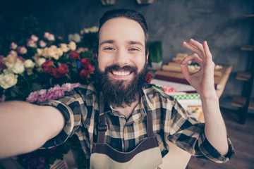 Self-portrait of his he nice attractive content cheerful cheery glad positive guy enjoying life showing ok-sign cool good wearing checked shirt at modern industrial loft concrete style salon indoors