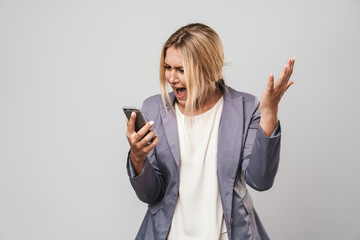 Fototapeta premium Amazing confused young pretty woman posing isolated over grey wall background using mobile phone.