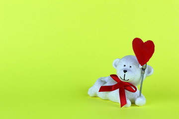 The figure of a white bear lying on his stomach ,holding a red heart.