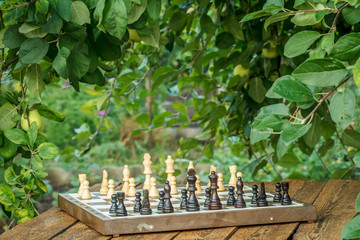 Chess board with chess pieces on wooden desk with natural background