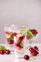 Summer strawberry sweet cherry cocktail ice cold drink in glasses on gray background.