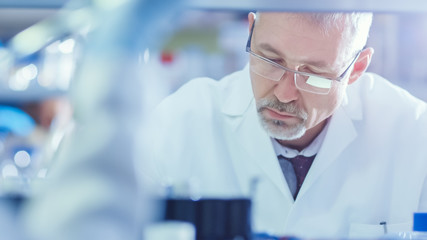 Genetic Research Senior Scientist is Sitting at the Table and working with Tube Samples in a Modern...