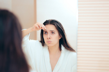 Fototapeta premium Woman Wearing Bathrobe Plucking her Eyebrows After Shower