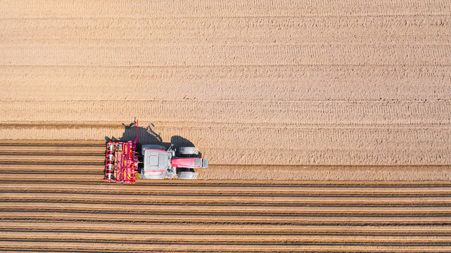 Tractor on a plowed field, top view. Agricultural field for planting vegetables. Tractor makes furrows on the field.