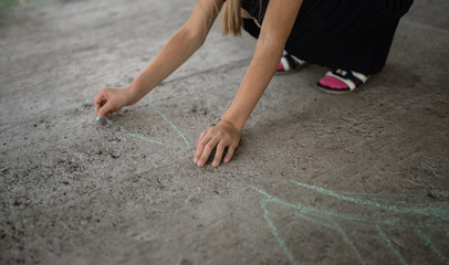 Close-up of a little girl and boy in canvas shoes with chalk on the sidewalk. a piece of chalk. draw on asphalt