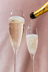Prosecco flutes and a bottle, an italian sparkling wine on pink romantic background