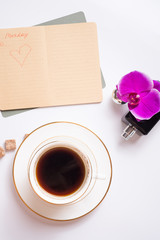 Obraz na płótnie Canvas cup of coffee with diary and perfume around white background. life style flat lay