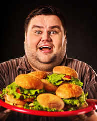 Fat man eats burgers. Obeseness and gluttony of fast food hamburger concept.