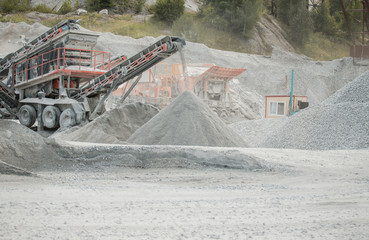Cement production factory on mining quarry. Conveyor belt of heavy machinery loads stones and gravel. Industrial background with working gravel crusher