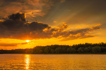 Fototapeta na wymiar Orange romantic sunset over lake on a beautiful summer evening.