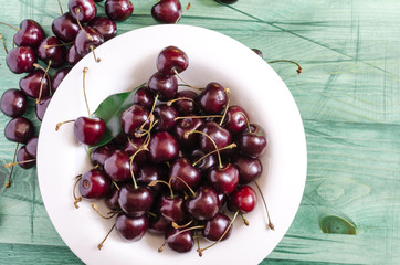 ripe cherry in a white dish on a green natural background