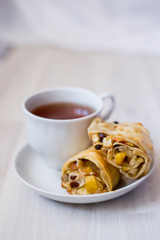 cup of tea and a piece of apple strudel on a saucer