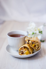 cup of tea and a piece of apple strudel on a saucer