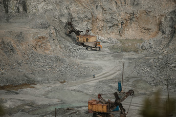 Cement production factory on mining quarry. Conveyor belt of heavy machinery loads stones and gravel. Industrial background with working gravel crusher