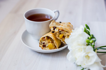 cup of tea and a piece of apple strudel on a saucer