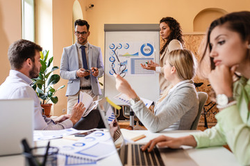 Group of young business people working together in office, two coworker conducting a business presentation using flip chart.