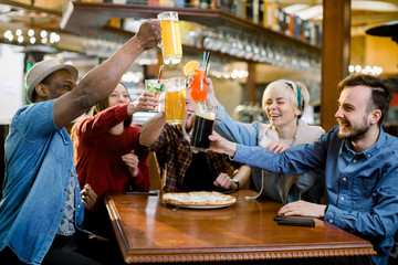 Excited diverse friends football fans celebrating victory goal score watching game online on tv in cafe supporting winning team drinking beer eating pizza together