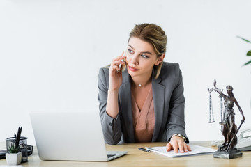 serious lawyer sitting in office, looking away and talking on smartphone