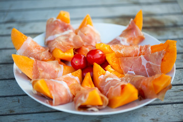 Melon with parma ham on garden table