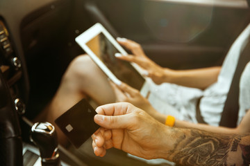 Obraz premium Young couple preparing for vacation trip on the car in sunny day. Woman and man sitting and ready for going to sea, riverside or ocean. Concept of relationship, vacation, summer, holiday, weekend.