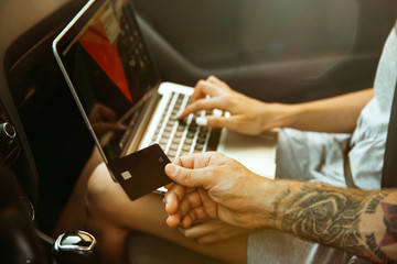 Young couple preparing for vacation trip on the car in sunny day. Woman and man sitting and ready for going to sea, riverside or ocean. Concept of relationship, vacation, summer, holiday, weekend.