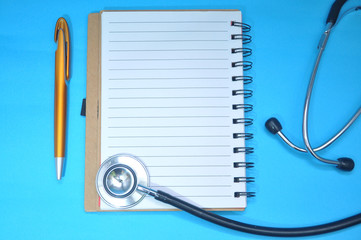 Blank notebook and medical stethoscope top view. Doctor’s work table concept. Health care concept